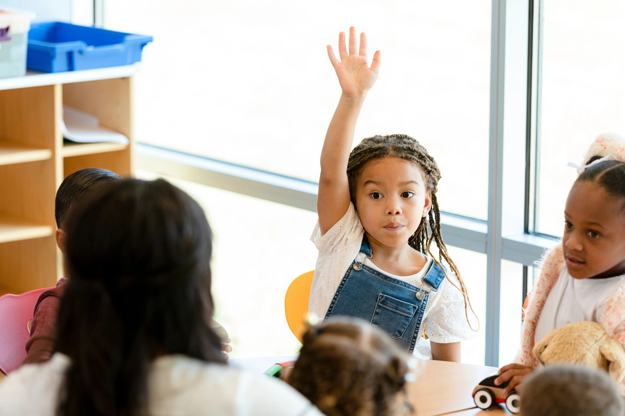 Child raising hand during preschool activity
