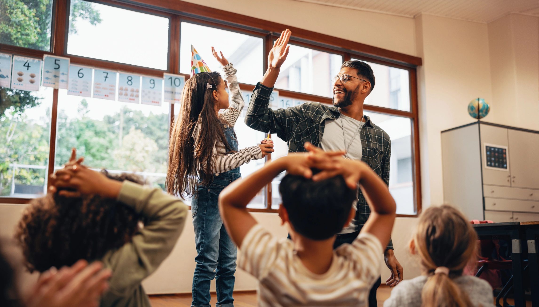 Teacher giving a high five to a student in a bright classroom
