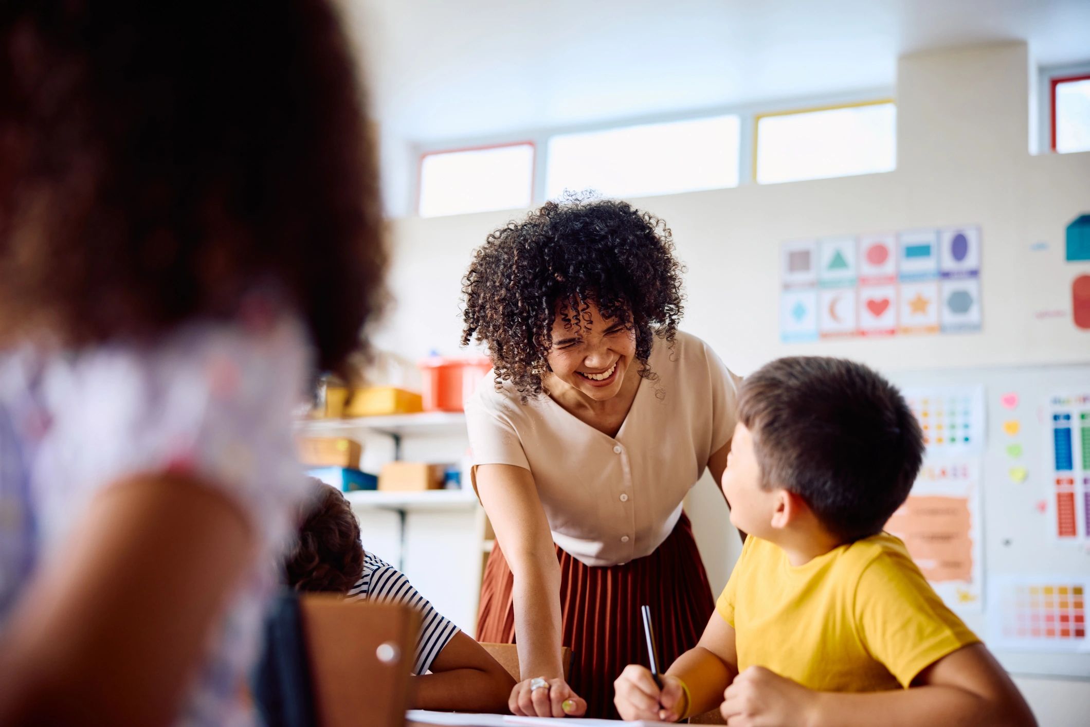 Teacher helping a child at a classroom desk