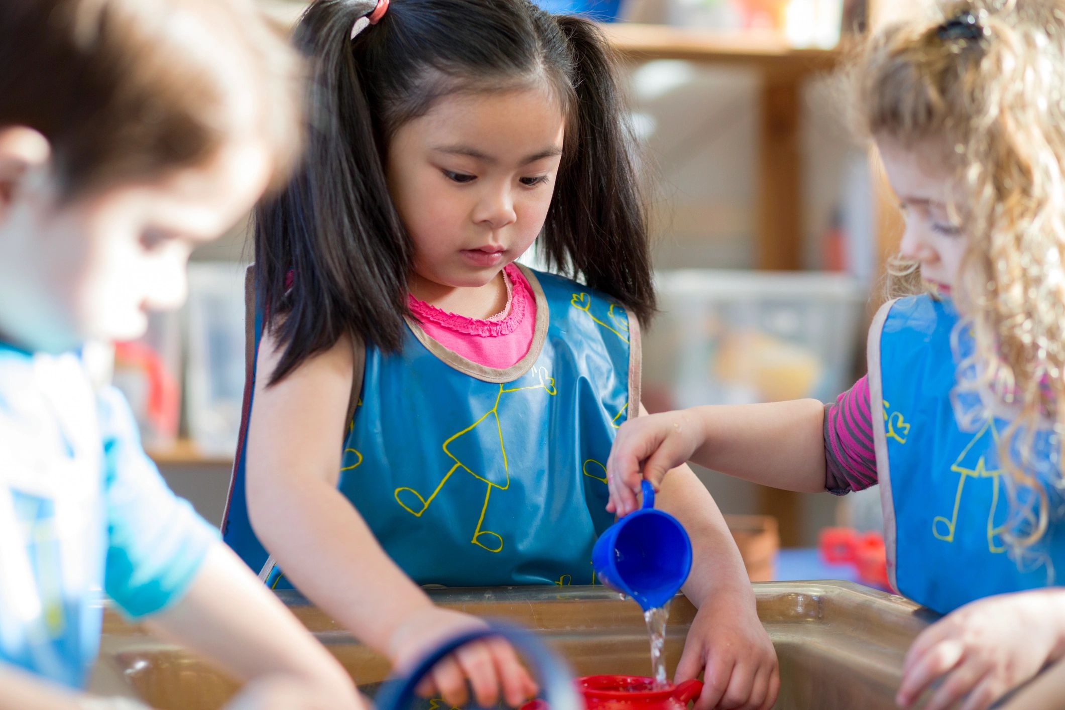 Young children playing together at a water table